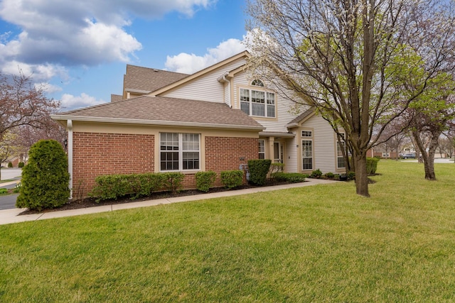 traditional-style home featuring brick siding, a shingled roof, and a front lawn