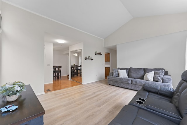 living area with visible vents, baseboards, vaulted ceiling, and light wood finished floors