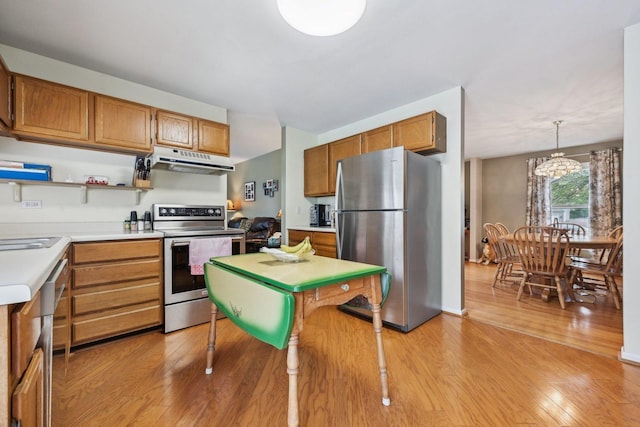 kitchen with a chandelier, stainless steel appliances, light wood finished floors, light countertops, and under cabinet range hood