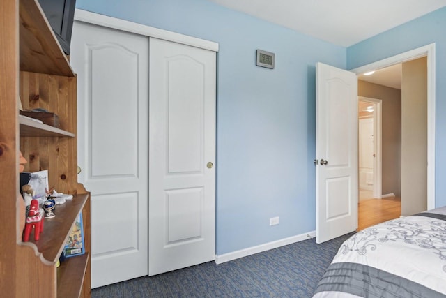 bedroom featuring dark carpet, a closet, and baseboards