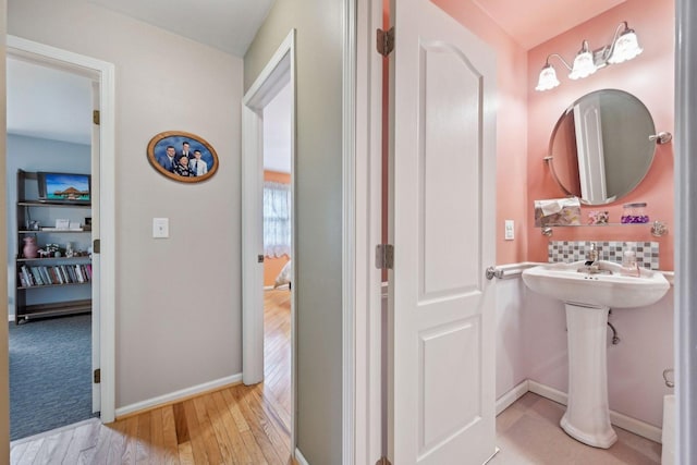 bathroom with baseboards, tasteful backsplash, and wood finished floors