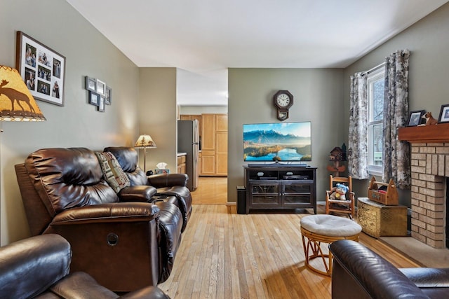 living room featuring a fireplace, baseboards, and light wood-type flooring