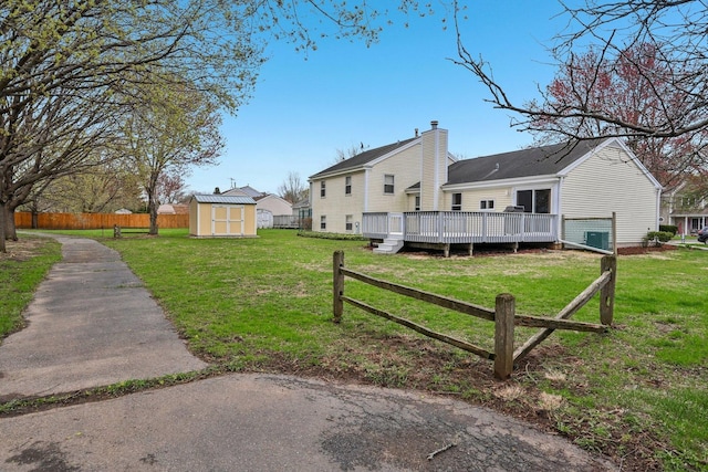 view of side of property with an outbuilding, fence, a lawn, a deck, and a shed