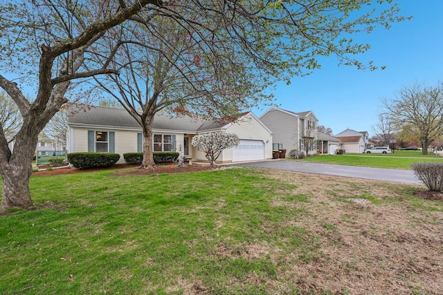view of front of property featuring an attached garage, aphalt driveway, and a front yard