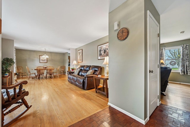 living room with baseboards, wood finished floors, and an inviting chandelier