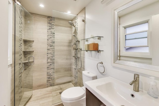 bathroom featuring toilet, a stall shower, recessed lighting, and vanity
