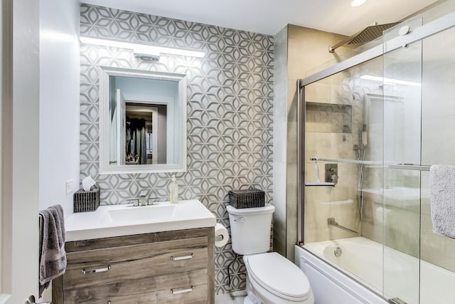 full bathroom featuring enclosed tub / shower combo, vanity, toilet, wallpapered walls, and tile walls