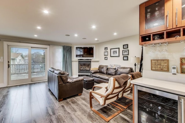 living area featuring wine cooler, a dry bar, light wood-type flooring, a glass covered fireplace, and recessed lighting
