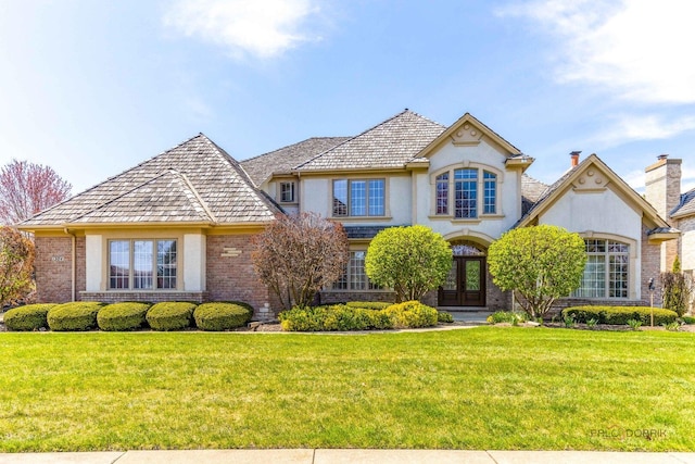 view of front of property featuring brick siding, a front lawn, and french doors