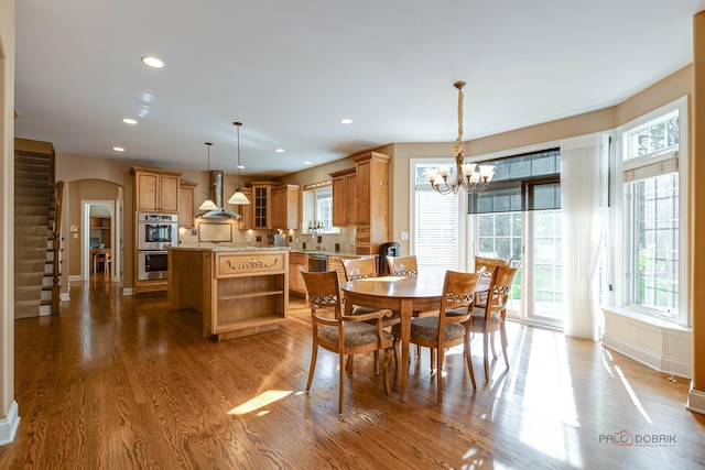 dining room featuring an inviting chandelier, arched walkways, recessed lighting, baseboards, and wood finished floors