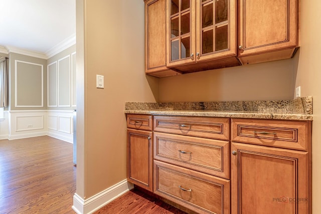 bar featuring baseboards, ornamental molding, a decorative wall, and dark wood-type flooring