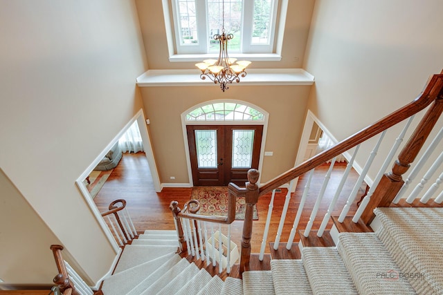 foyer entrance with a chandelier, wood finished floors, stairway, and a towering ceiling