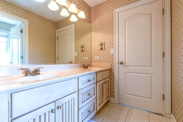bathroom featuring wallpapered walls, a chandelier, a sink, and tile patterned flooring