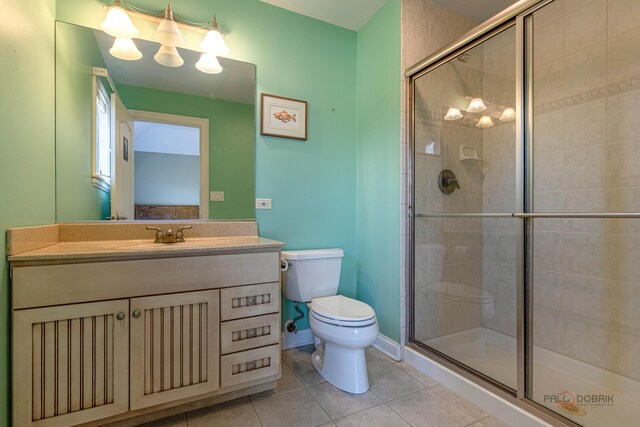 full bathroom featuring tile patterned flooring, vanity, toilet, baseboards, and a shower stall