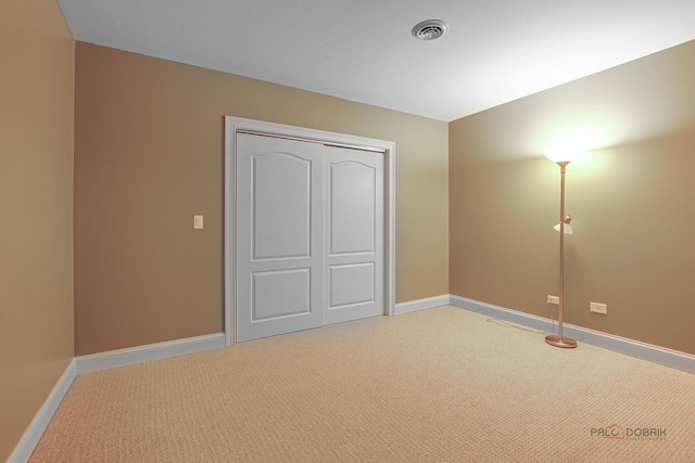 unfurnished bedroom featuring visible vents, baseboards, a closet, and light colored carpet