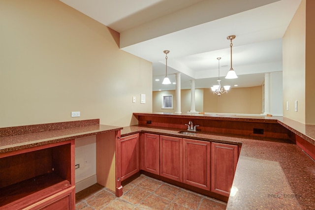 bar with a chandelier, pendant lighting, and a sink