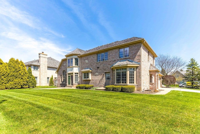 back of property with a lawn and brick siding