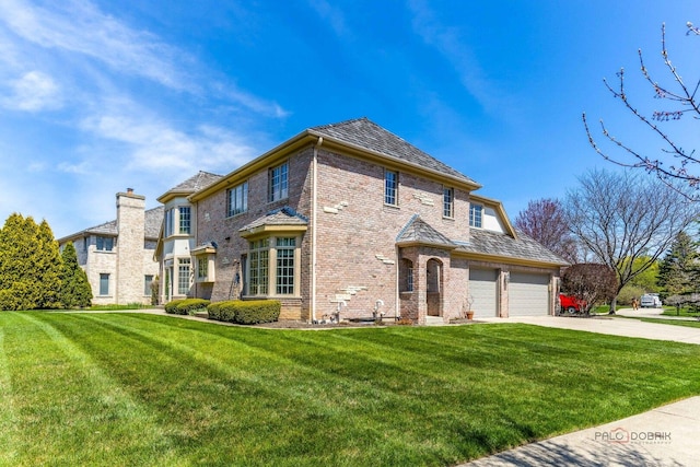 view of front of home featuring an attached garage, concrete driveway, a front lawn, and brick siding