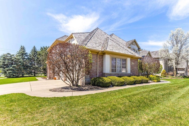 view of side of home with a lawn, brick siding, and driveway