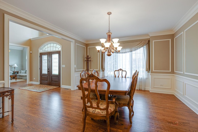 dining space with a notable chandelier, ornamental molding, and wood finished floors
