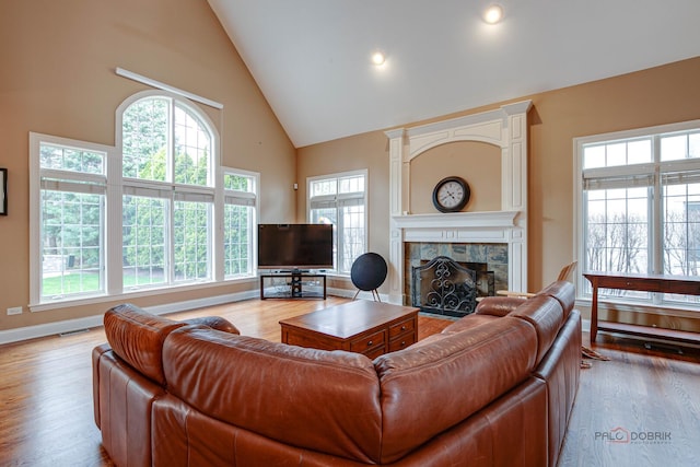 living room featuring a stone fireplace, a wealth of natural light, and high vaulted ceiling