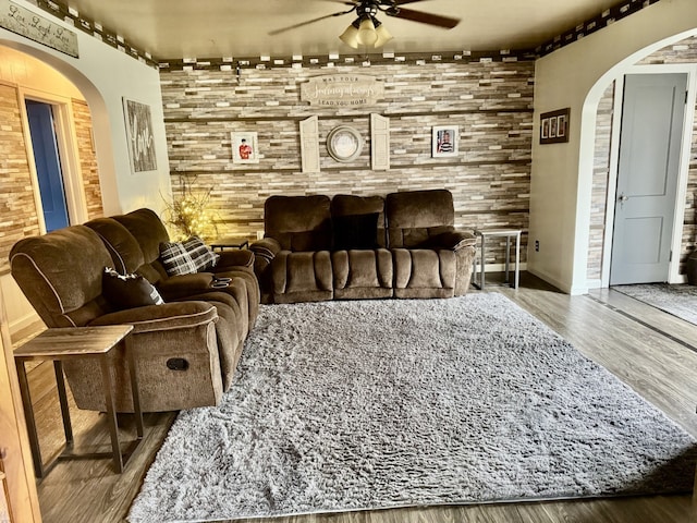 living room with ceiling fan, wood finished floors, and arched walkways