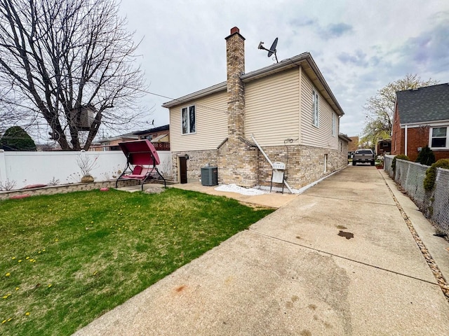 8129 45th Pl, Lyons, IL 60534 - rear view of house featuring central AC unit, a chimney, concrete driveway, fence, and a yard