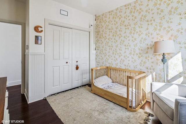 bedroom with a closet, wood finished floors, and wallpapered walls