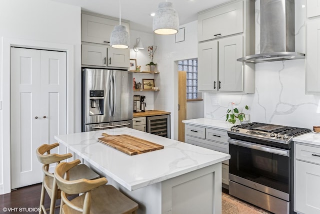 kitchen with wall chimney range hood, open shelves, light stone counters, beverage cooler, and stainless steel appliances