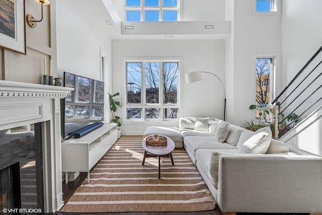 living area featuring baseboards, stairs, a towering ceiling, and a premium fireplace