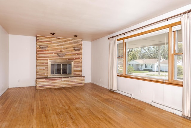 unfurnished living room featuring a fireplace, wood finished floors, plenty of natural light, and baseboards