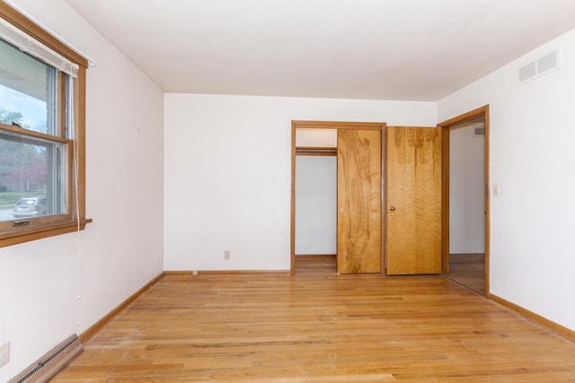 unfurnished bedroom with baseboard heating, visible vents, light wood finished floors, and baseboards