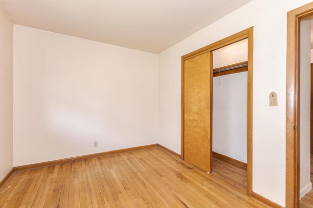 unfurnished bedroom with baseboards, a closet, and light wood finished floors