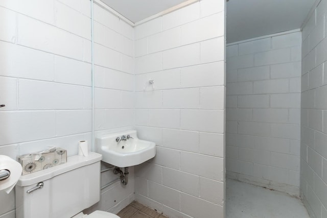 bathroom featuring toilet and a tile shower