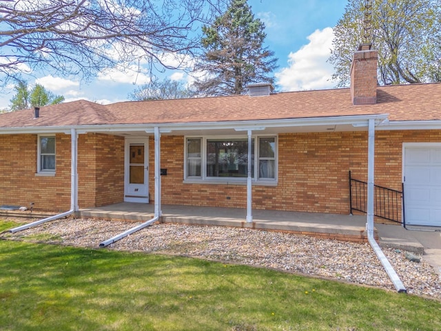 exterior space with a chimney, brick siding, a porch, and an attached garage