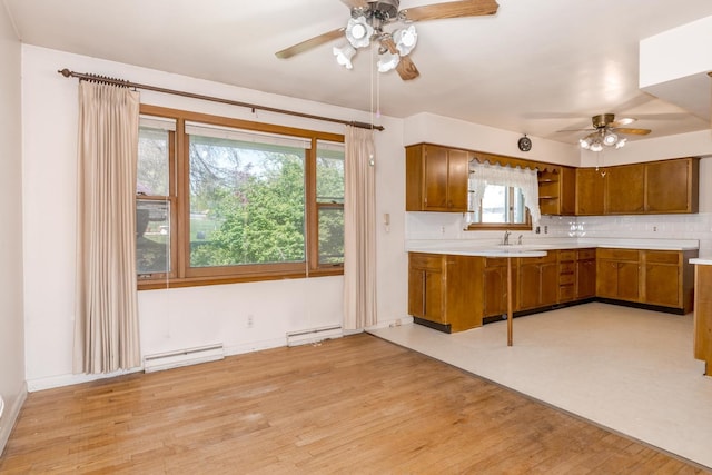 kitchen featuring a baseboard heating unit, a ceiling fan, brown cabinetry, and light countertops