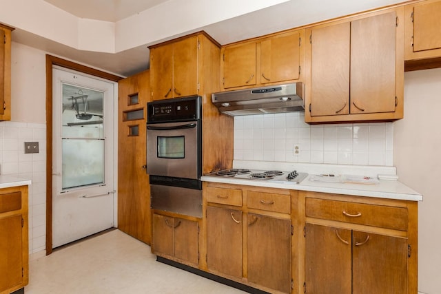 kitchen with light countertops, under cabinet range hood, electric stovetop, oven, and backsplash