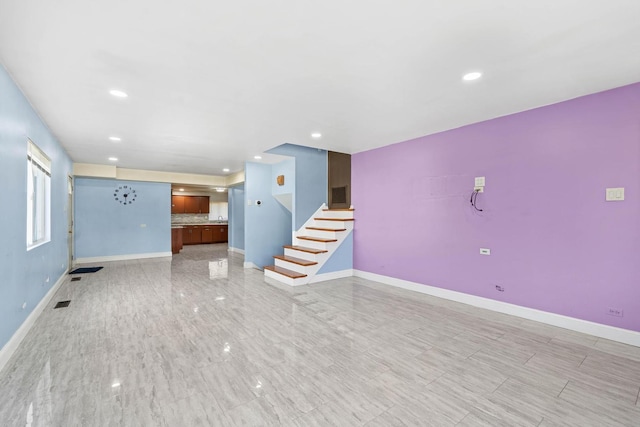unfurnished living room with baseboards, recessed lighting, and stairway