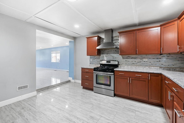 kitchen featuring wall chimney range hood, gas stove, baseboards, and decorative backsplash