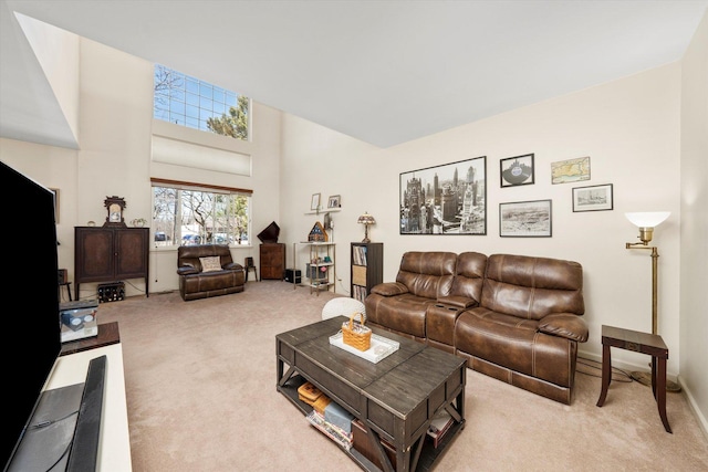 carpeted living area with a high ceiling and baseboards