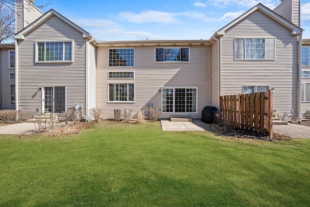 back of property with a lawn, a patio, a chimney, and fence