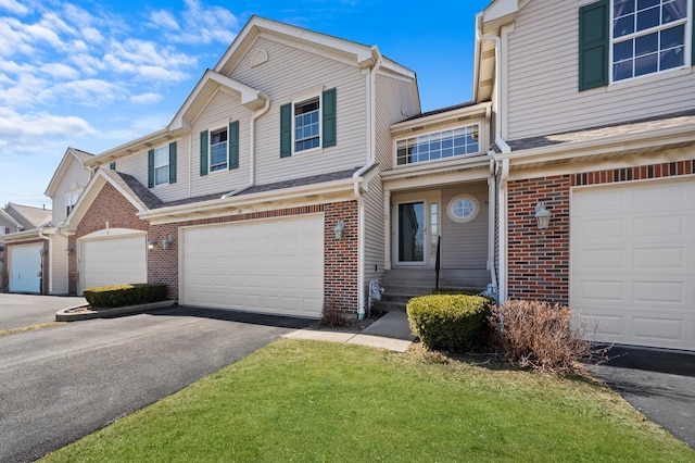 townhome / multi-family property with an attached garage, brick siding, and driveway