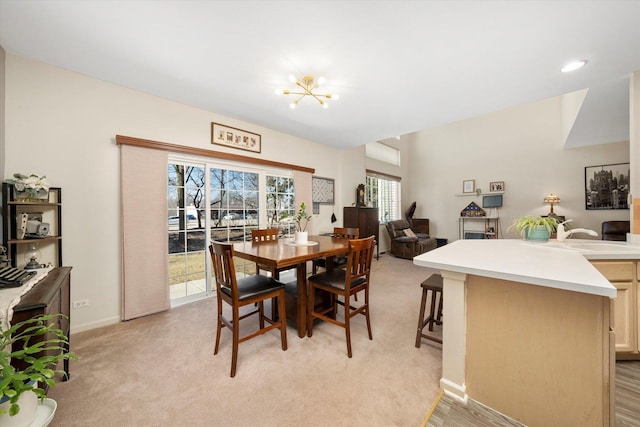 dining area featuring baseboards, a chandelier, and light colored carpet