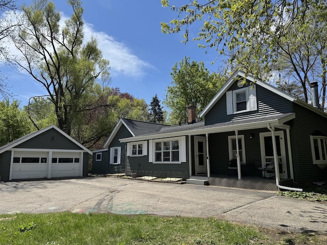 view of front of home featuring covered porch, an outdoor structure, a garage, and a chimney