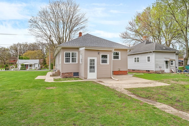 112 W 1st St, Streator, IL 61364 - back of house featuring roof with shingles, a chimney, a yard, and a patio