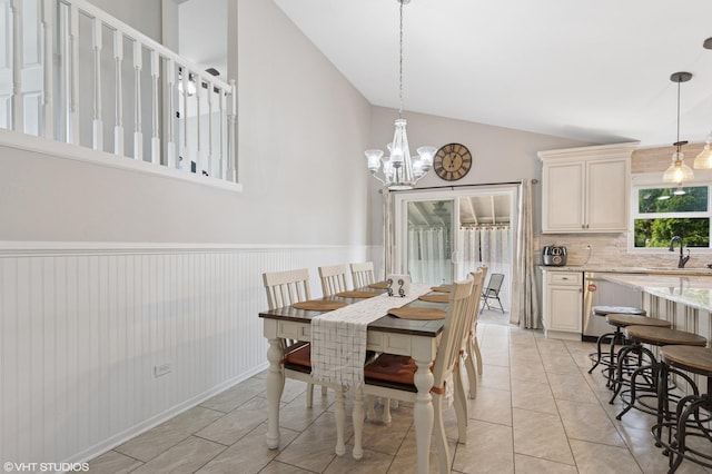 dining room featuring wainscoting, a notable chandelier, light tile patterned flooring, and vaulted ceiling