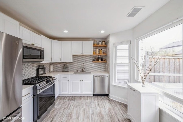 kitchen with white cabinets, appliances with stainless steel finishes, a sink, and light countertops