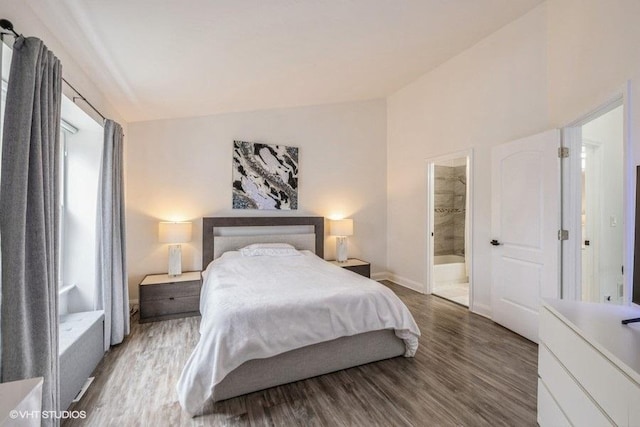 bedroom featuring ensuite bath, baseboards, vaulted ceiling, and wood finished floors