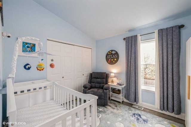bedroom featuring vaulted ceiling, a closet, wood finished floors, and visible vents