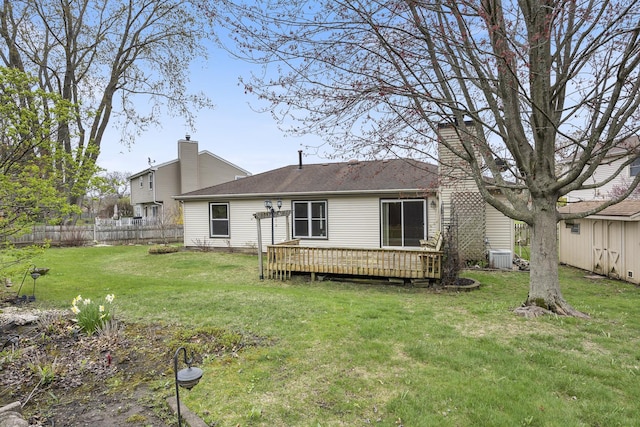 rear view of property with central AC unit, a chimney, fence, a deck, and a yard